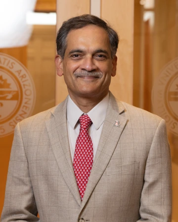 Suresh Garimella standing in front of glass doors with the U of A seal on them. 